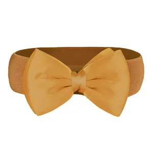 Detailed macro view of large mustard yellow satin bow on wide elastic waist cincher belt