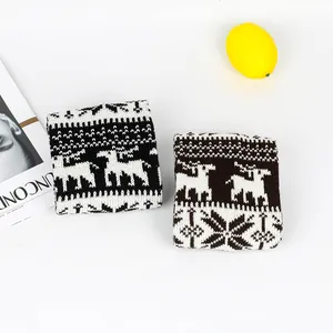 Detail shot of thick knitted leg warmers with Christmas reindeer and snowflake patterns.