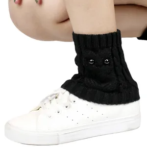 Close-up of black knit owl patterned leg warmers styled over white sneakers for winter