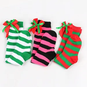 Detail view of colorful striped children's knee-high socks with festive red green bows