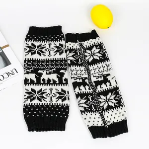 Detailed view of knitted leg warmers featuring black and white Christmas reindeer patterns.