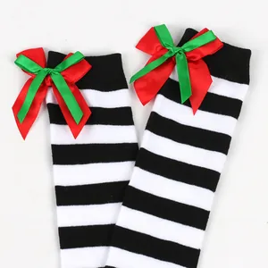 Detailed view of girls' black and white striped over-the-knee socks with red and green bows.