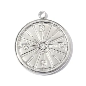 Detail of stainless steel compass pendant with clear central gemstone in silver finish.