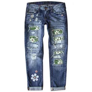 Detailed view of women's slim-fit blue jeans featuring floral patches and camo accents