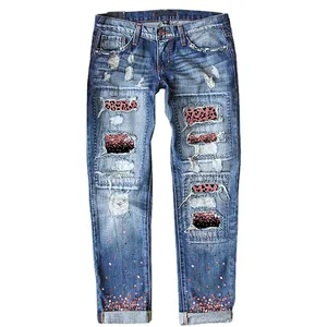 Detail of women's ripped slim-fit denim jeans with leopard print patches and sequins
