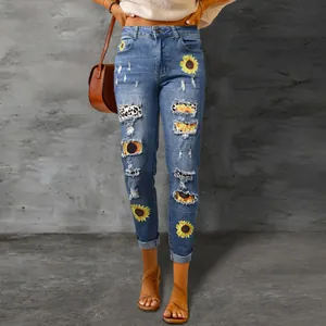 Detail of distressed denim jeans featuring sunflower prints and leopard patches.