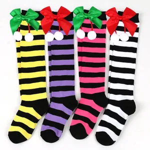 Detailed view of children's striped knee-high socks with festive bows and pom-poms