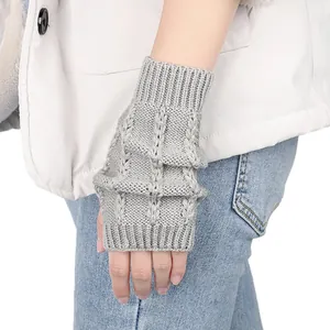 Nahaufnahme von grau gestrickten fingerlosen Armstulpen mit strukturiertem Zopfmuster