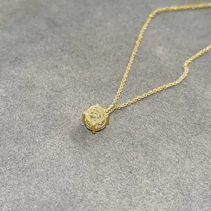 Detailed view of a 14k gold plated moissanite pendant necklace on grey background.
