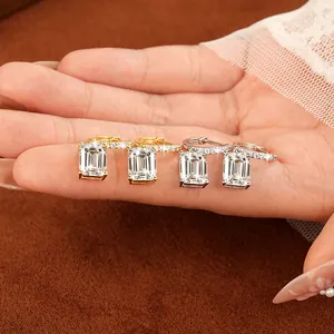 Close-up of emerald cut moissanite hoop earrings in gold and silver finish on hand