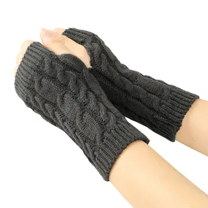 Macro view showing the intricate dark grey cable knit pattern on fingerless winter gloves.
