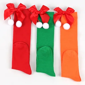 Festive children's long socks with red bows and white pom-poms in three vibrant colors.