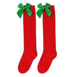 Detailed view of red Christmas knee-high socks with green satin bows for girls