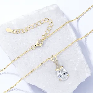 Dettaglio di un'elegante collana con pendente in moissanite dorata a forma di pera su pietra