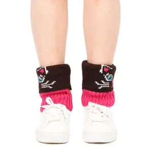 Détail de jambières tricotées avec motif cartoon marron et rose vif et baskets blanches