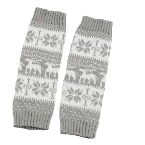 Close-up of gray and white knitted leg warmers with snowflake and deer patterns.