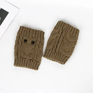 Detailed macro view of brown cable-knit owl leg warmers featuring decorative button eyes