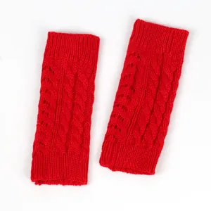 Close-up view of red cable knit fingerless gloves with intricate hollow-out pattern details.