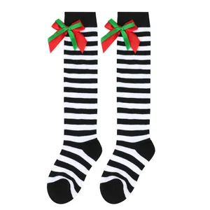 Close-up of children's striped knee-high Christmas socks with red and green bows