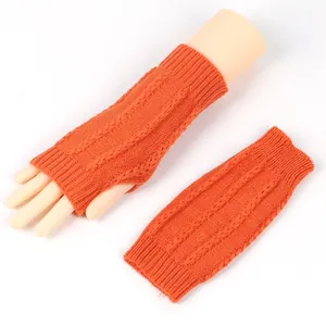 Detailansicht der orangefarbenen Zopfstrick-Armstulpen mit weicher Texturierung