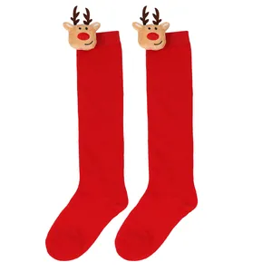 Close-up of red children's Christmas long socks with cute plush reindeer heads at the cuff.
