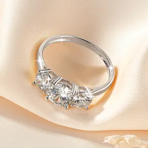 Κοντινό πλάνο με τρεις πέτρες Moissanite σε ασημένιο δαχτυλίδι σε μεταξωτό φόντο.