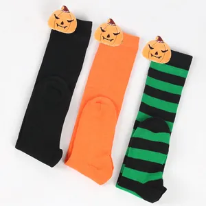Close-up detail of three Halloween socks with plush pumpkin heads on white background