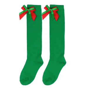 Detail of festive green girl's over-the-knee socks with red and green bows.