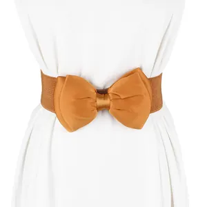 Close-up of a large golden chiffon bow on a wide elastic waist belt for dresses