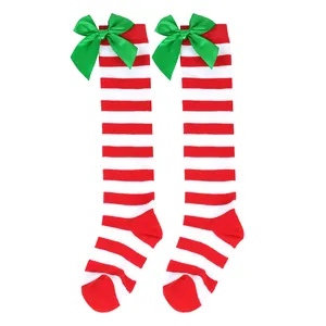 Festive red and white striped girls' knee-high socks with green satin bows on white background