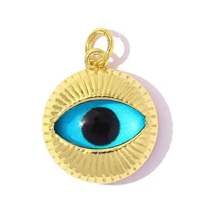 Close-up of gold-plated circular pendant with blue and black evil eye design detail