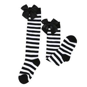 Detail view of black and white striped knee-high socks with large satin bows.