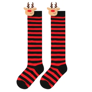 Close-up of children's Christmas long socks with red stripes and reindeer plush dolls