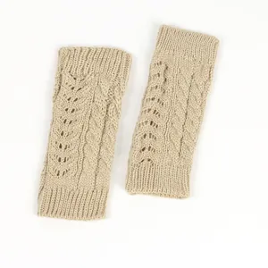Close-up of beige cable knit fingerless gloves with hollow-out pattern detail.