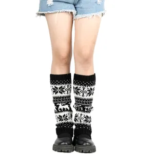 Detailed view of Christmas snowflake and reindeer patterned knitted leg warmers on legs.