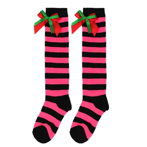 Close-up of pink and black striped knee-high socks with festive red and green bows