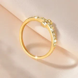 Κοντινό πλάνο κομψού δαχτυλιδιού σταυρού 14k με λαμπερές πέτρες σε σατέν φόντο