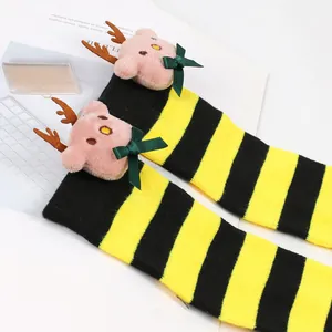 Detail view of plush reindeer doll on yellow and black striped Christmas socks