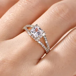 Nahaufnahme eines silbernen Rings mit quadratischem Zirkon und kreuzförmigem Design.