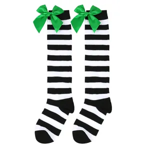 Close-up detail of girls' black and white striped knee-high socks with green satin bows