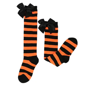 Detail view of orange and black striped Halloween socks with decorative black silk bows.