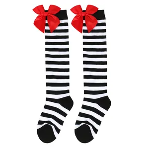Detail view of children's black and white striped knee-high socks with red satin bows