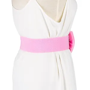 Close-up detail of a wide pink elastic waist belt with a chiffon bow on a dress