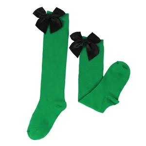 Detailed view of children girls green knee-high socks with elegant black satin bows decoration