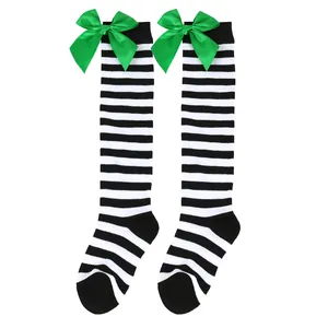 Close-up view of girls' black and white striped knee-high socks with green bows