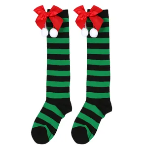Close-up of green and black striped Christmas socks with red bows and white pom-poms