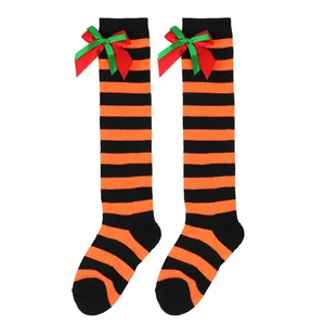 Close-up of children's orange and black striped knee-high socks with festive bows