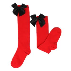 Detailed view of red girls' knee-high socks featuring large black satin bows