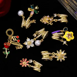 Close-up of gold-plated zircon charms with flower, rose, and musical note designs.