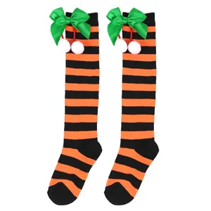 Detail of children's orange and black striped knee socks with green bow and pom-poms